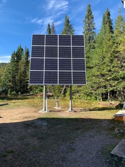 Champ solaire de huit modules monté sur poteaux en clairière, installation réalisée par Sol-Air Tech