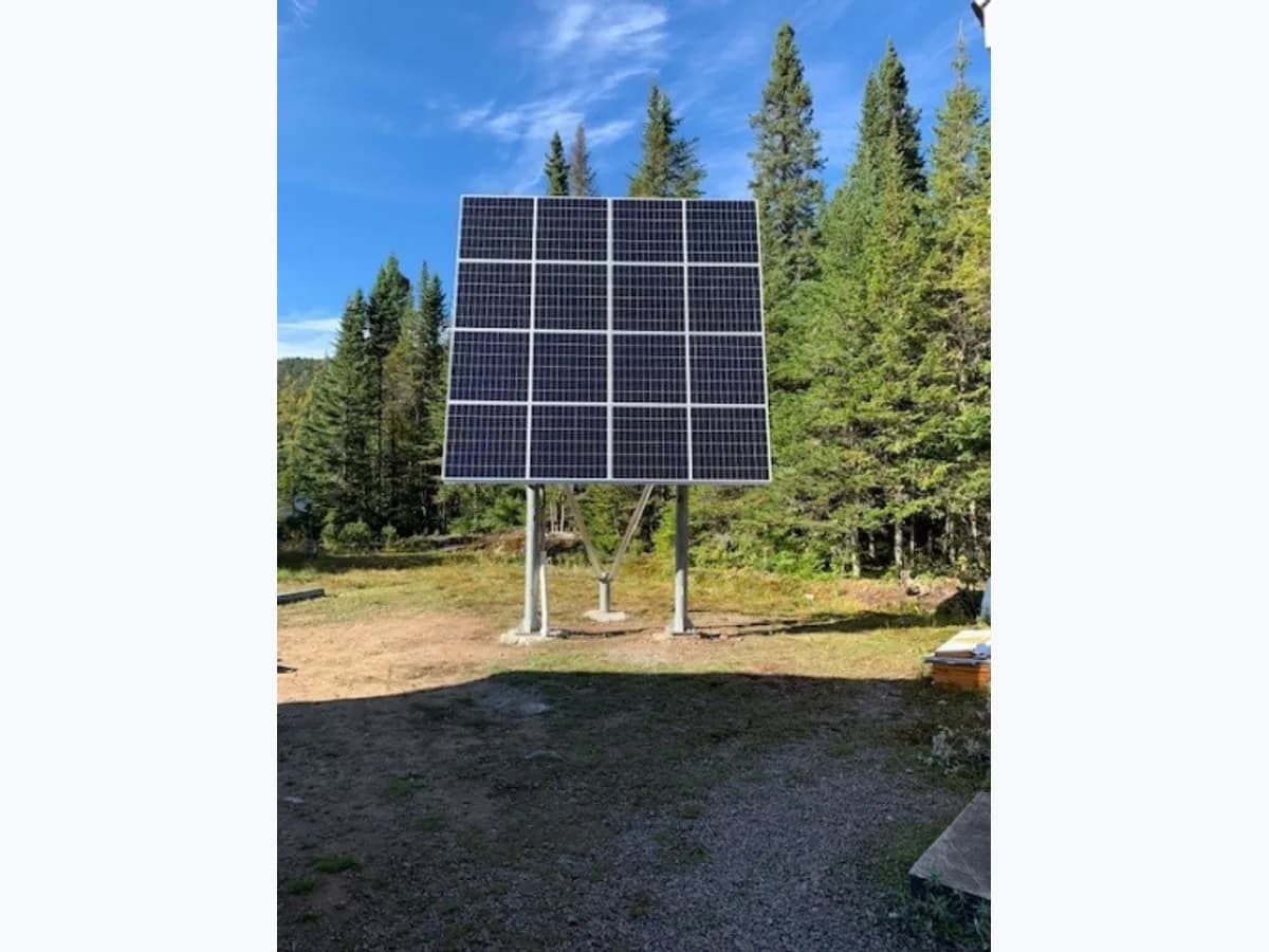 Trois modules solaires sur support au sol dans une clairière boisée