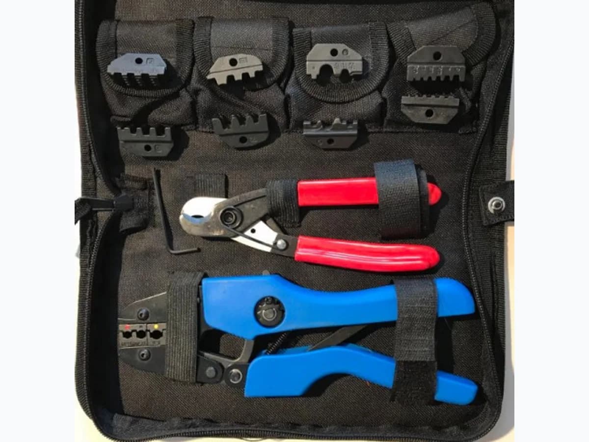 Trousse de sertissage ouverte : pince à cliquet, matrices et coupe-câble rangés dans leur étui